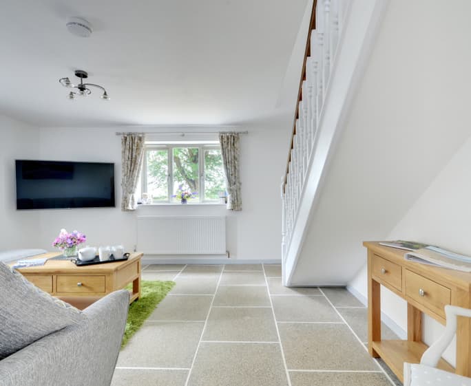The warm and comfortable living room has a large Smart TV and picture window