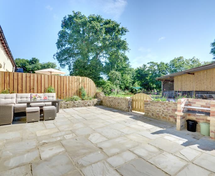 The private paved patio area with relaxed seating, table and barbecue