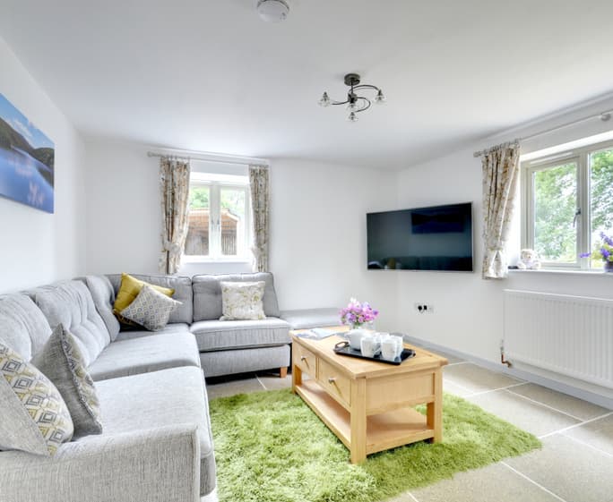 The warm and comfortable living room has a large Smart TV and picture window