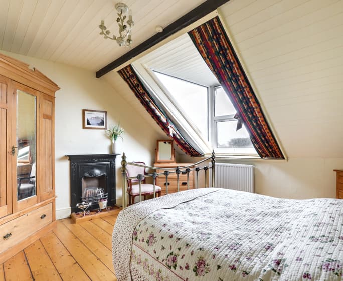 The stylish master bedroom on the second floor enjoys wonderful sea views in one direction and beautiful countryside views in the other 