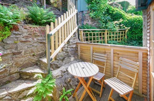 French doors open on to the rear decked terrace and patio area, steep steps lead up into the raised and layered gardens
