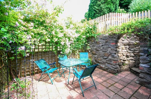 French doors open on to the rear decked terrace and patio area, steep steps lead up into the raised and layered gardens