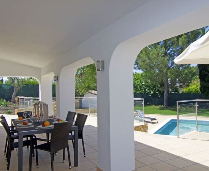 Covered terrace with table and chairs overlooking the swimming pool