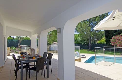 Covered terrace with table and chairs overlooking the swimming pool