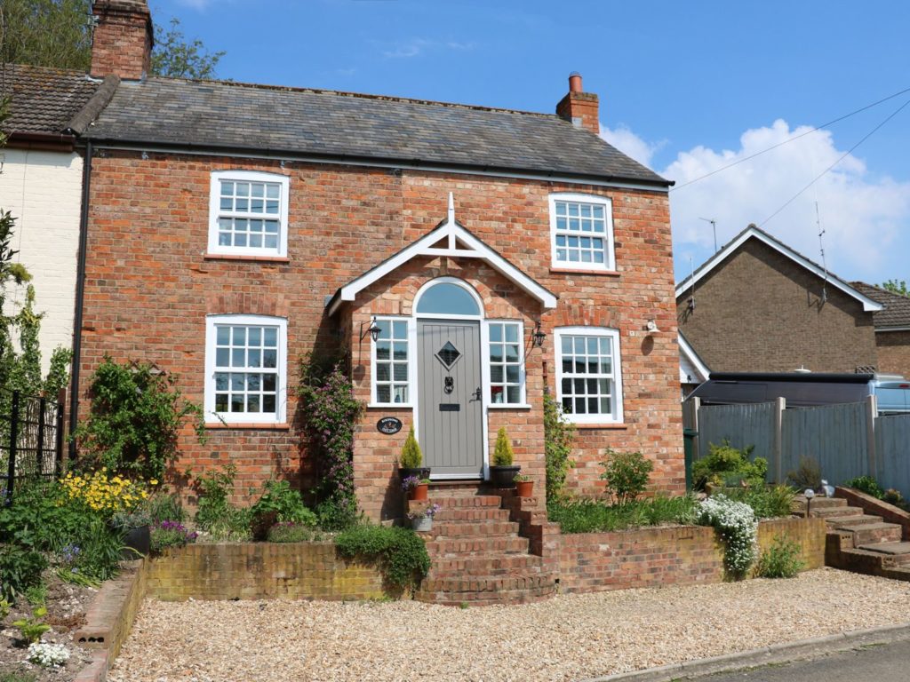 a semi-detached brick cottage with steps up to the front door
